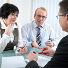 Two individuals having a discussion with a man on the other side of the table